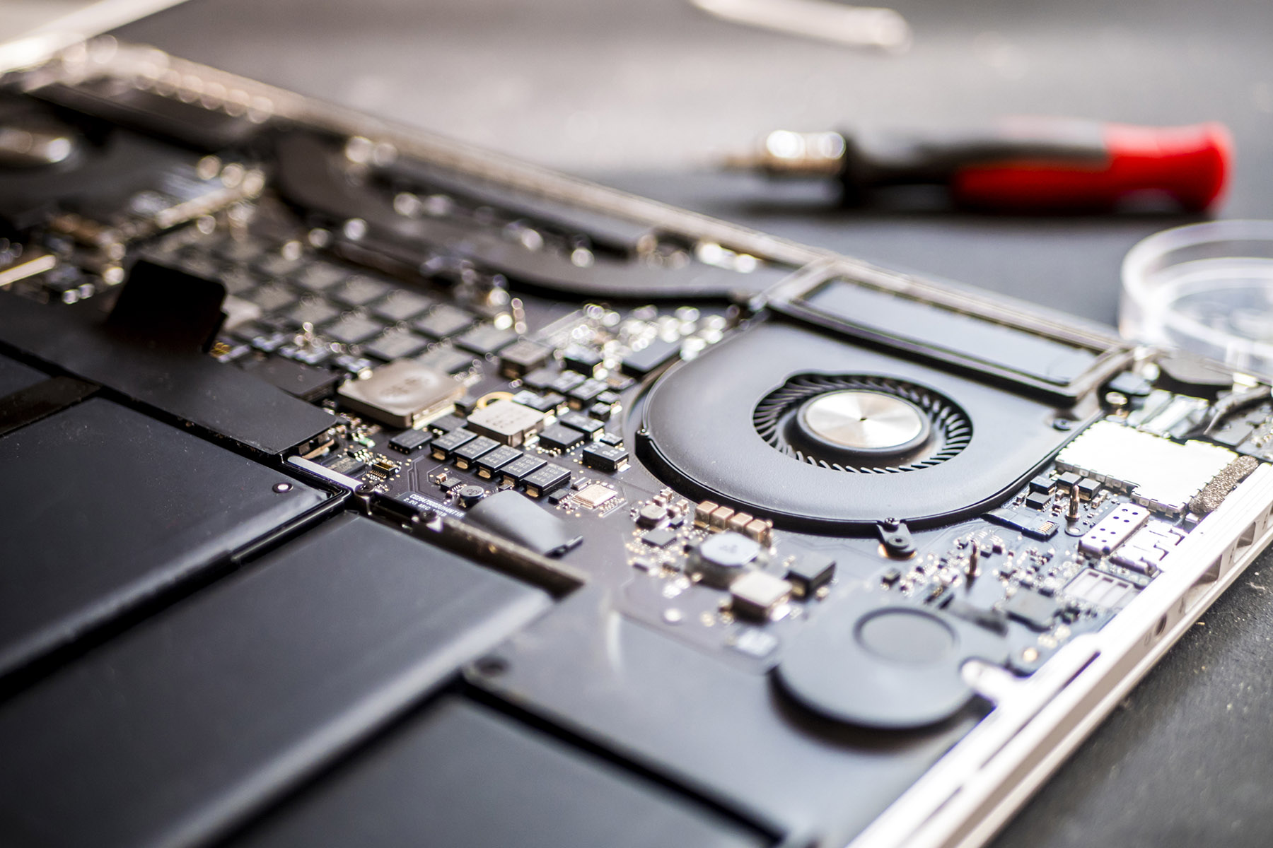 Technician carefully repairing a laptop motherboard